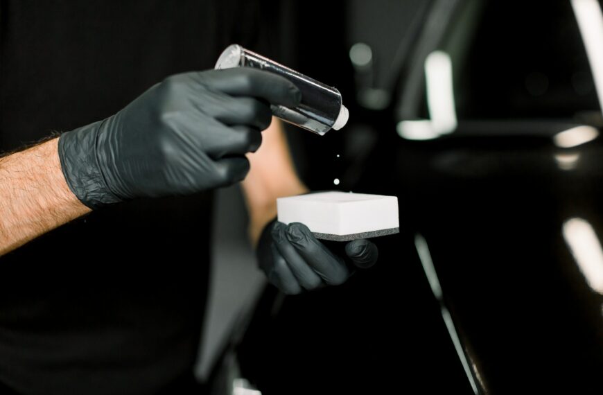 Cropped image of hands of male auto service worker in protective gloves, applying special polish