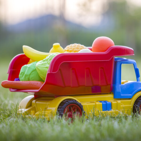 Bright plastic colorful toy car truck carrying basket with toy fruits and vegetables