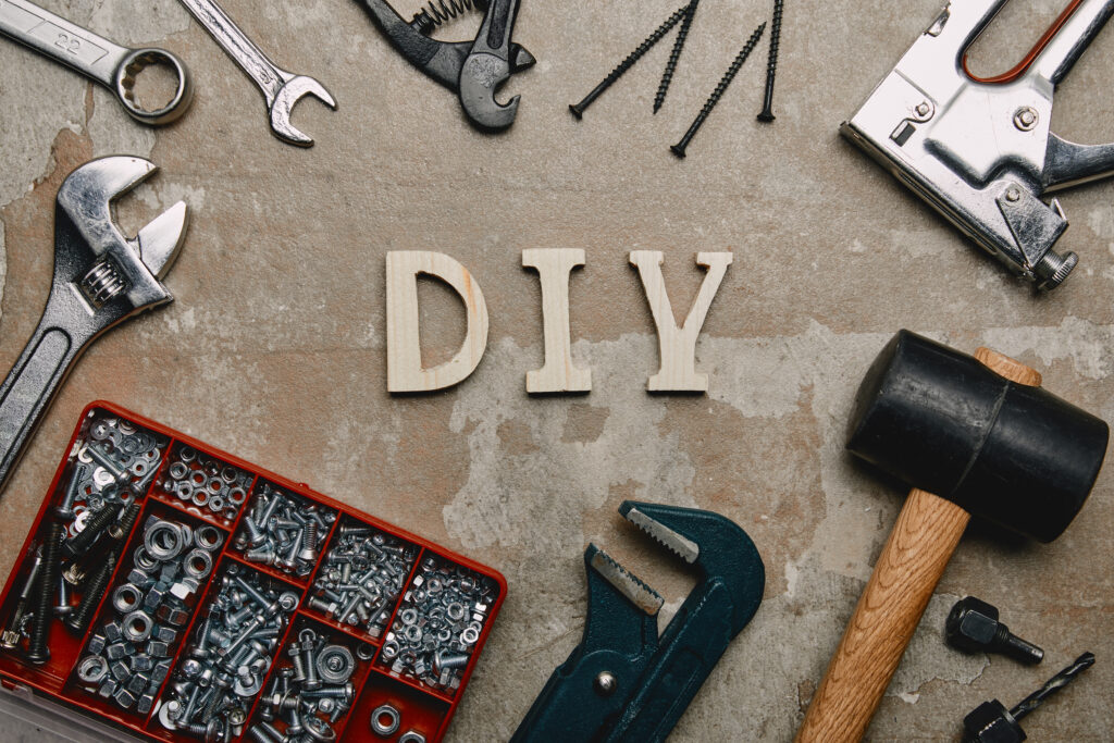 Top view of do it yourself sign and various carpentry tools arranged on old surface background