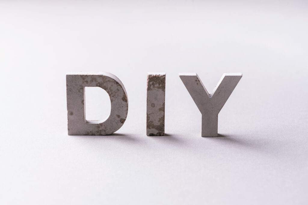 Word diy from cement letters on grey background. Do It Yourself abrreviation